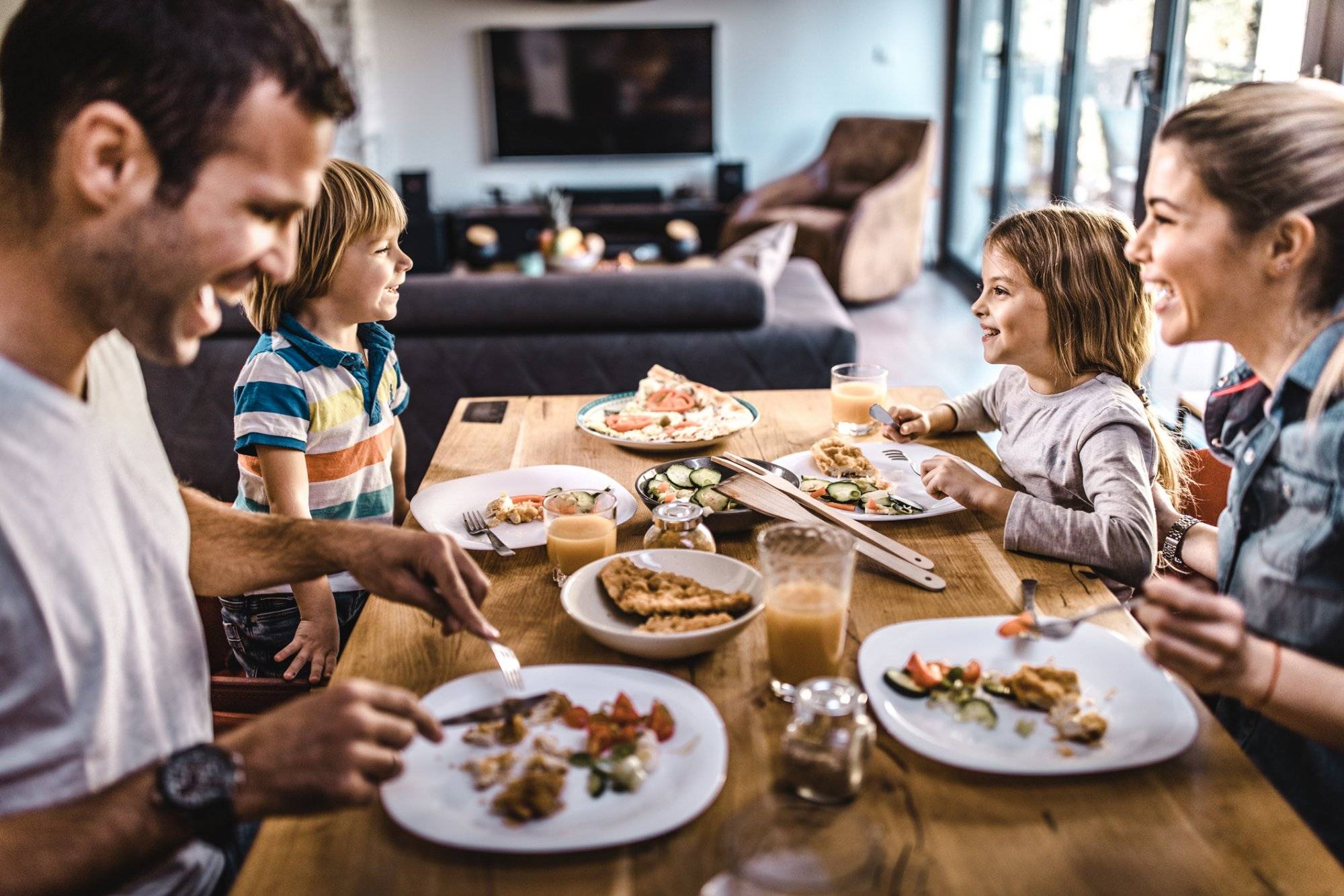 Young happy family talking while having lunch at dining table. Young happy family talking while having lunch at dining table.