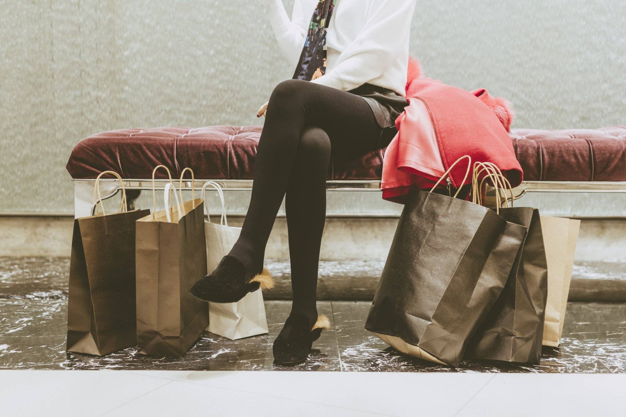 low section of woman sitting on sofa rest after shopping